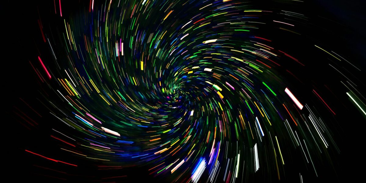 Dynamic spiral of colorful light trails on a dark background, captured with long exposure.