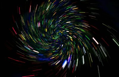 Dynamic spiral of colorful light trails on a dark background, captured with long exposure.