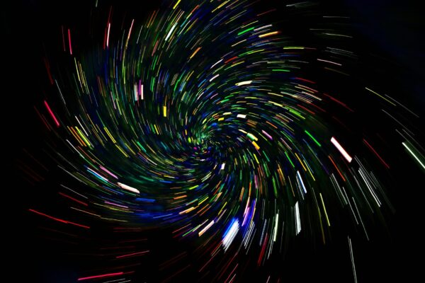 Dynamic spiral of colorful light trails on a dark background, captured with long exposure.
