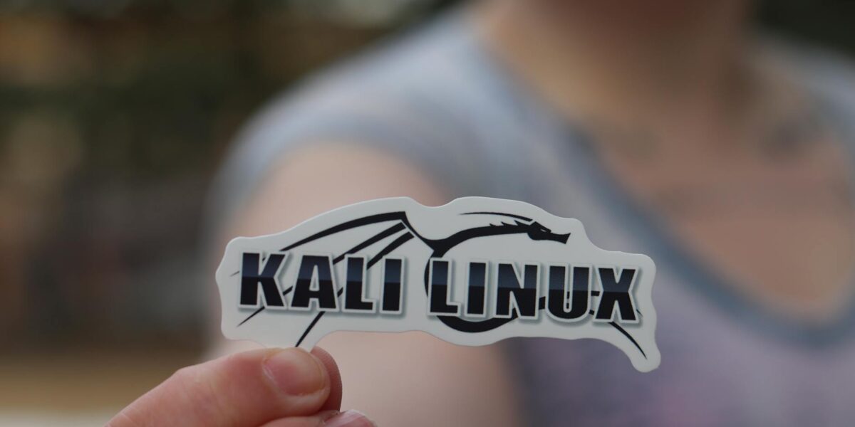 Close-up shot of a person holding a Kali Linux sticker, highlighting cyber security themes.