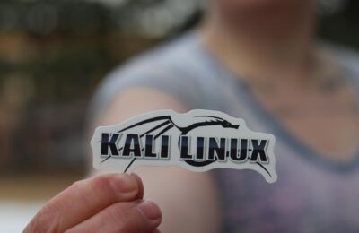 Close-up shot of a person holding a Kali Linux sticker, highlighting cyber security themes.