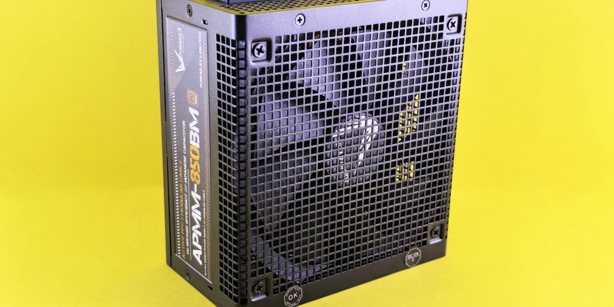Black computer power supply unit with fan displayed against yellow background.