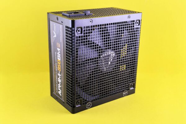 Black computer power supply unit with fan displayed against yellow background.