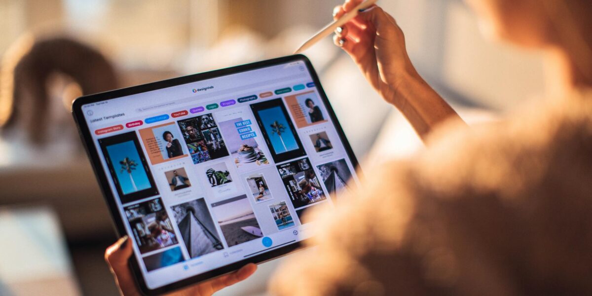 A person uses a digital tablet with a stylus indoors in a warm, cozy setting.