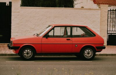 A classic red hatchback car parked beside a white stone wall in Torrevieja, Spain.