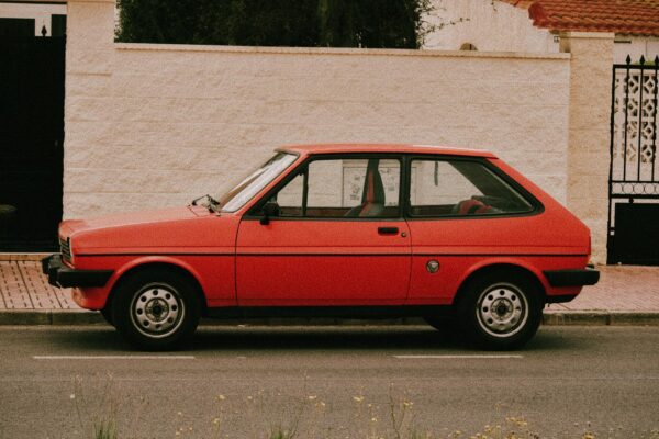 A classic red hatchback car parked beside a white stone wall in Torrevieja, Spain.