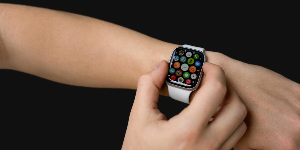 Close-up of hands using a smartwatch with app icons visible, representing modern technology.