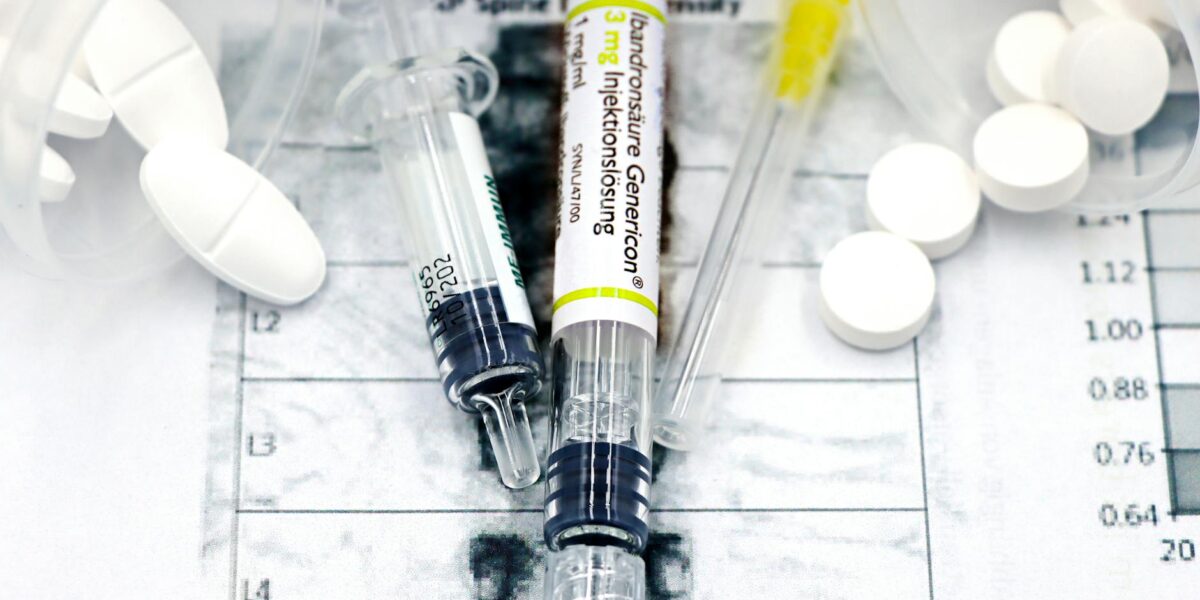 Close-up of syringes and pills on a bone density exam sheet, depicting osteoporosis treatment.