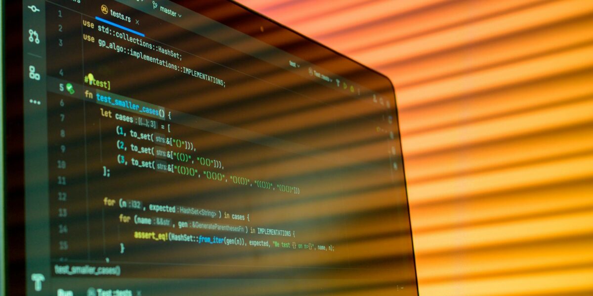 Blurry close-up of a computer screen displaying code with orange lighting.