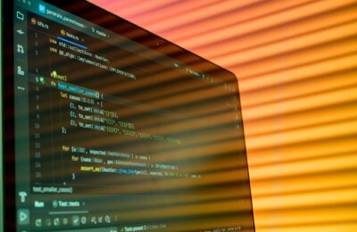 Blurry close-up of a computer screen displaying code with orange lighting.