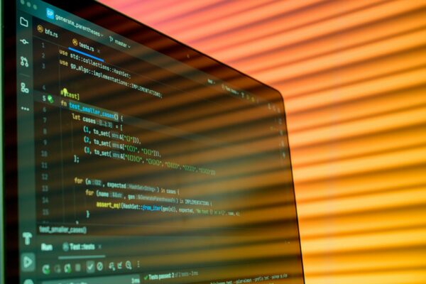 Blurry close-up of a computer screen displaying code with orange lighting.