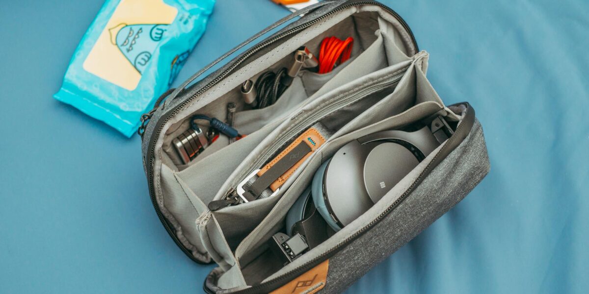 A top view of an organized travel tech bag filled with headphones, cables, and wipes.