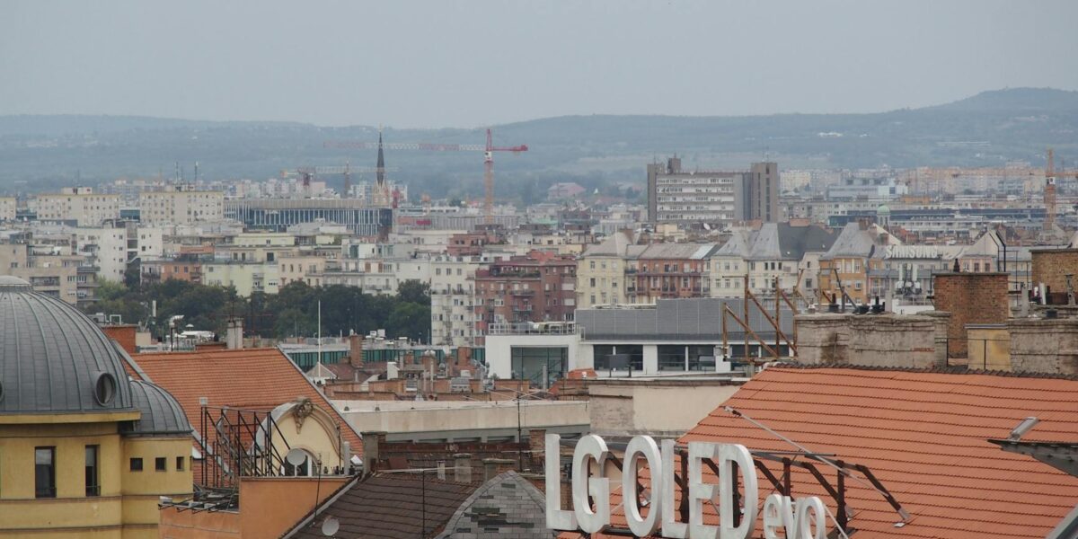 A cityscape above rooftops featuring an LG OLED sign against a distant urban backdrop.