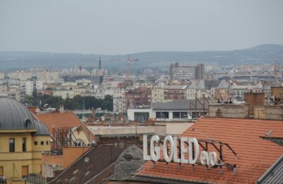 A cityscape above rooftops featuring an LG OLED sign against a distant urban backdrop.