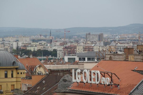 A cityscape above rooftops featuring an LG OLED sign against a distant urban backdrop.