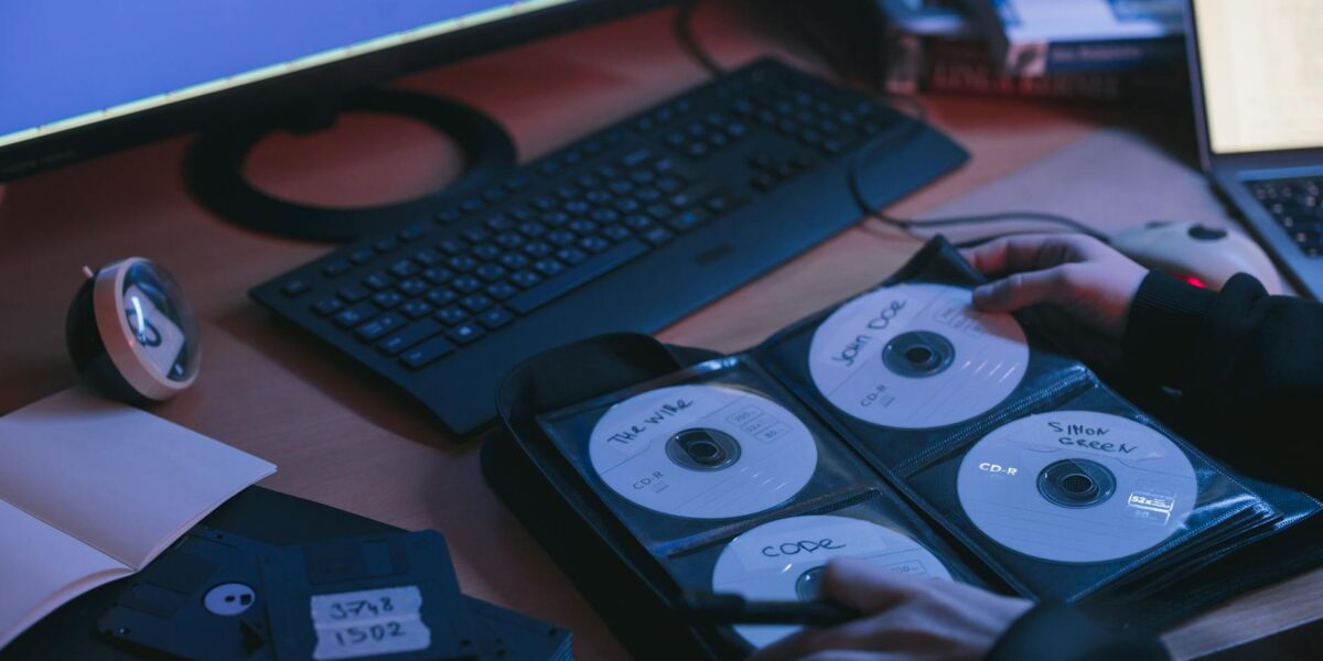 A close-up of CDs and disks on a desk, featuring hands in a tech environment.