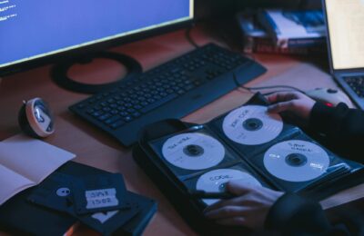 A close-up of CDs and disks on a desk, featuring hands in a tech environment.