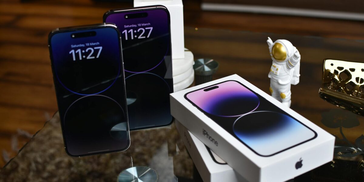 Close-up of Apple iPhone 14 Pro Max with astronaut figurine on a reflective surface.