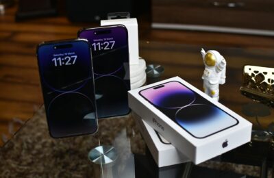 Close-up of Apple iPhone 14 Pro Max with astronaut figurine on a reflective surface.