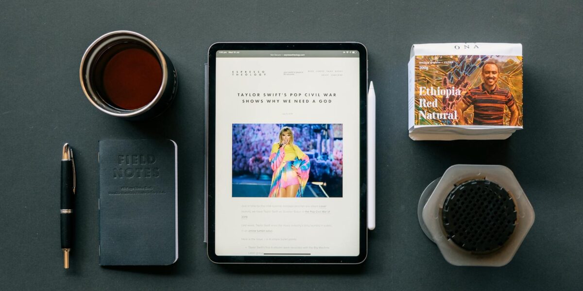 Flat lay of a tablet, coffee, and notebook on a desk, ideal for productivity themes.
