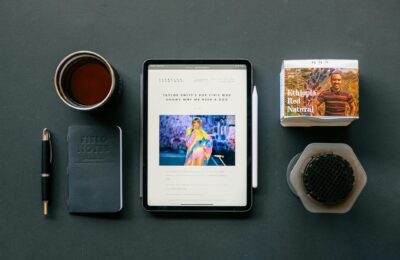 Flat lay of a tablet, coffee, and notebook on a desk, ideal for productivity themes.