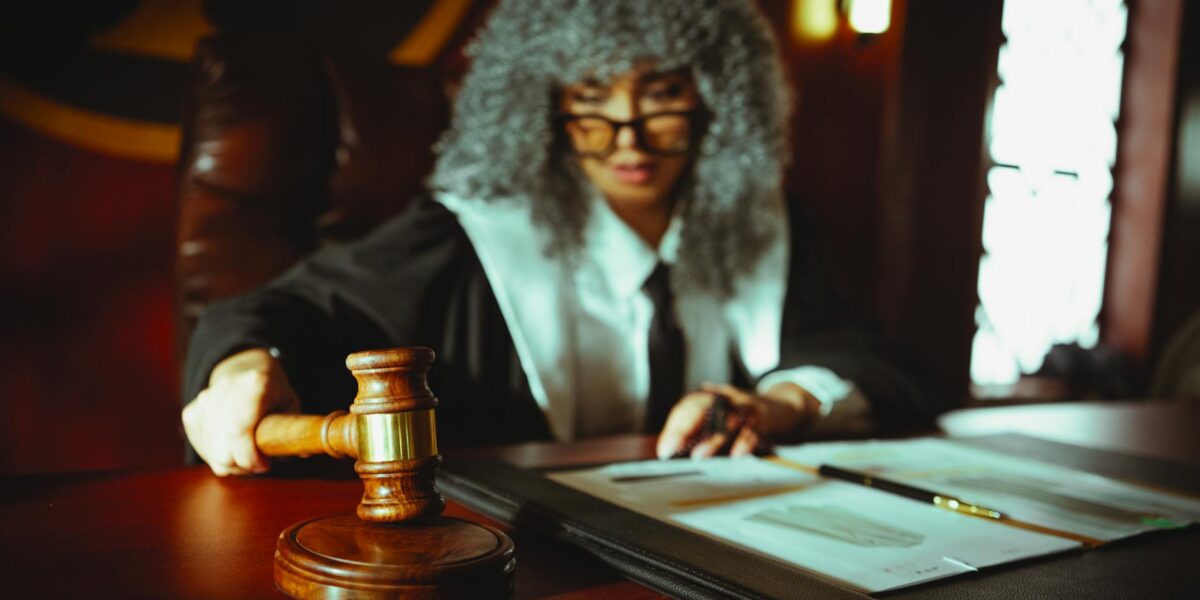 Female judge in a courtroom setting, focusing on legal documents with a gavel.