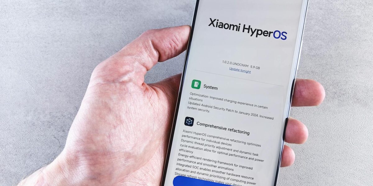 Close-up of a hand holding a Xiaomi smartphone with HyperOS interface, showcasing comprehensive refactoring and system update details.