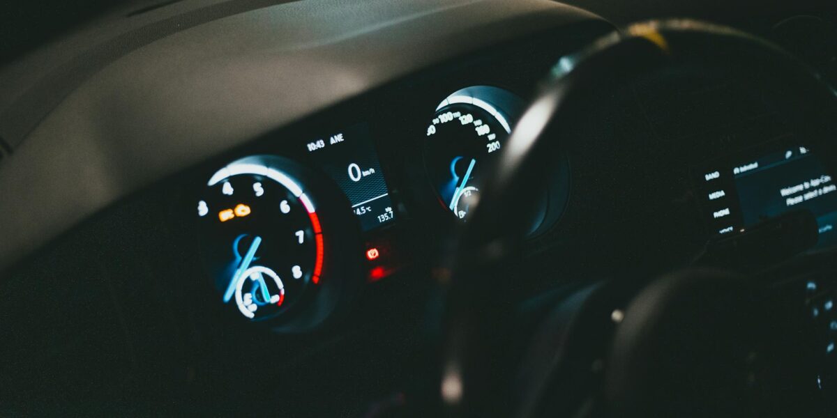 Detailed view of an illuminated car dashboard with speedometer and odometer visible.