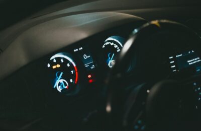Detailed view of an illuminated car dashboard with speedometer and odometer visible.