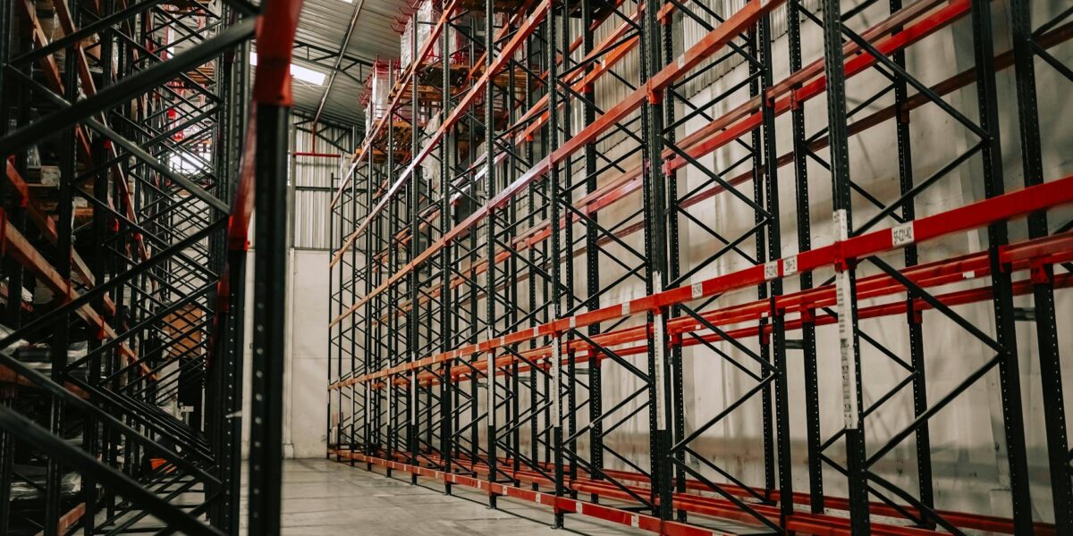 Spacious warehouse interior featuring empty metal racks and high ceiling.