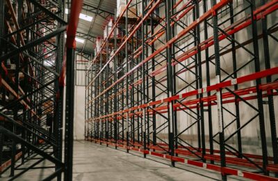 Spacious warehouse interior featuring empty metal racks and high ceiling.