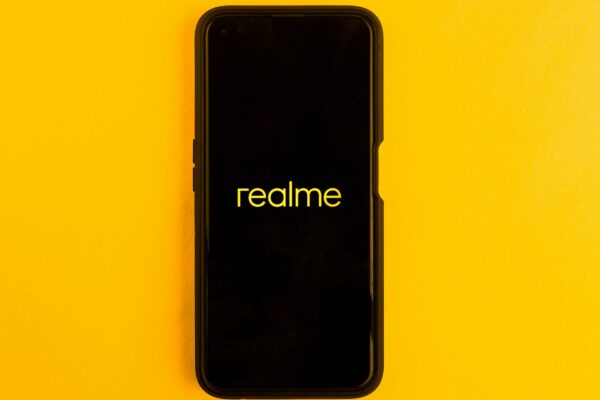 Realme smartphone displayed against a bright yellow backdrop, emphasizing modern technology.