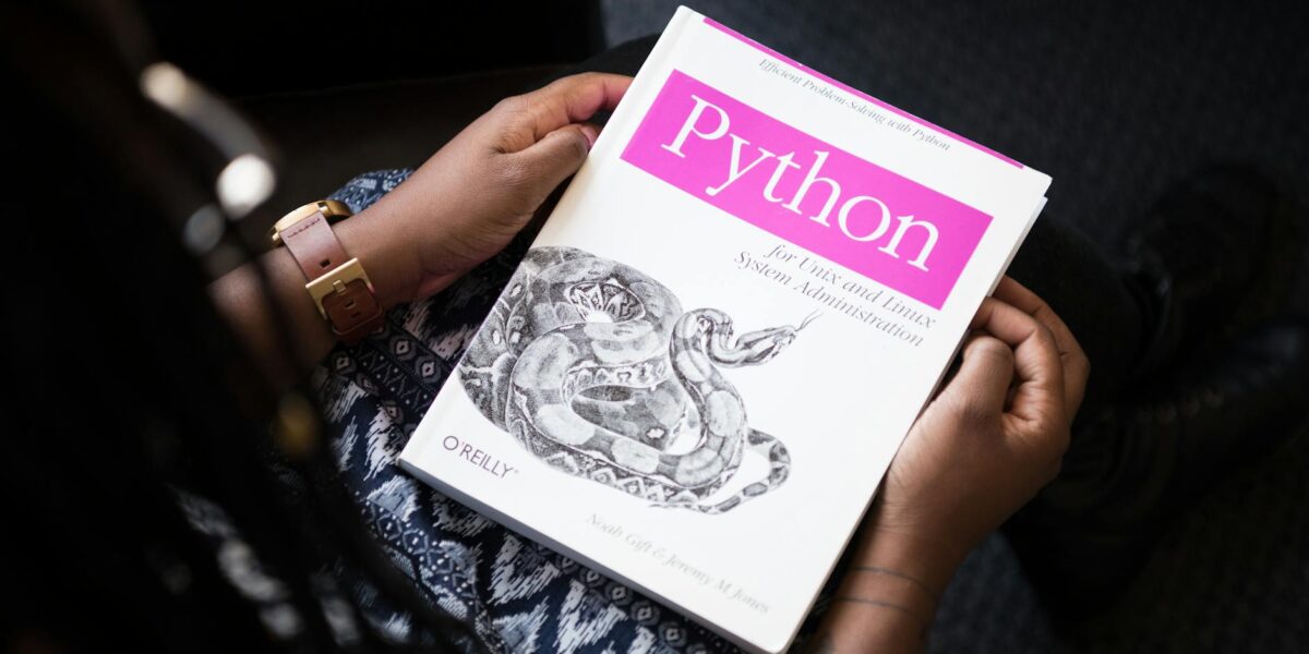 A person reads 'Python for Unix and Linux System Administration' indoors.