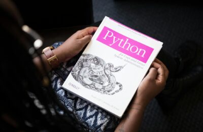 A person reads 'Python for Unix and Linux System Administration' indoors.