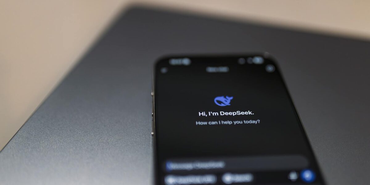 Close-up of a smartphone with AI assistant interface on screen over a laptop.