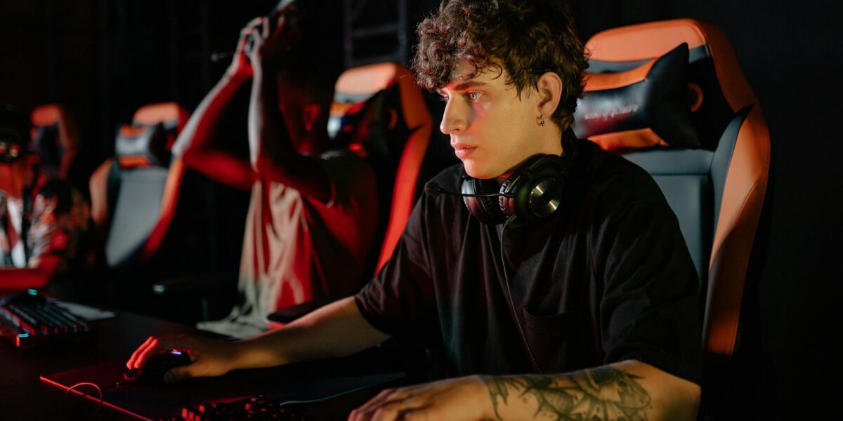 Competitive gamers in an esports tournament concentrating deeply in dimly lit setting.