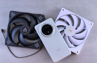 Image of a smartphone alongside two cooling fans on a textured gray surface.