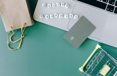 Flat lay of online shopping essentials with laptop, card, and shopping cart.