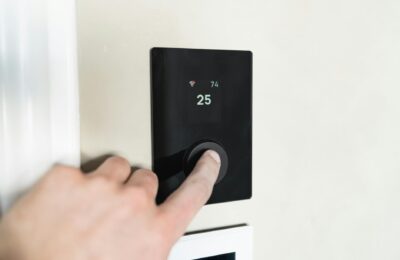 Close-up of a hand adjusting a sleek, modern smart thermostat on a wall.