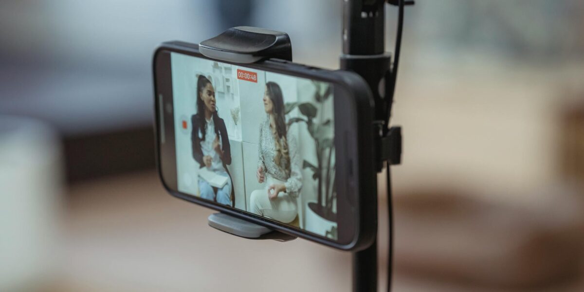 Modern smartphone on tripod recording video of content stylish women having friendly conversation