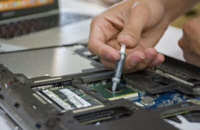 Close-up of hand applying thermal paste to a laptop microchip for maintenance.