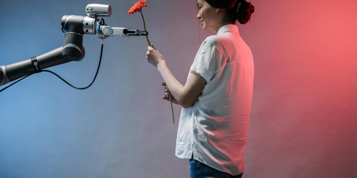 A woman interacts with a robotic arm holding a flower, showcasing technology and human connection.