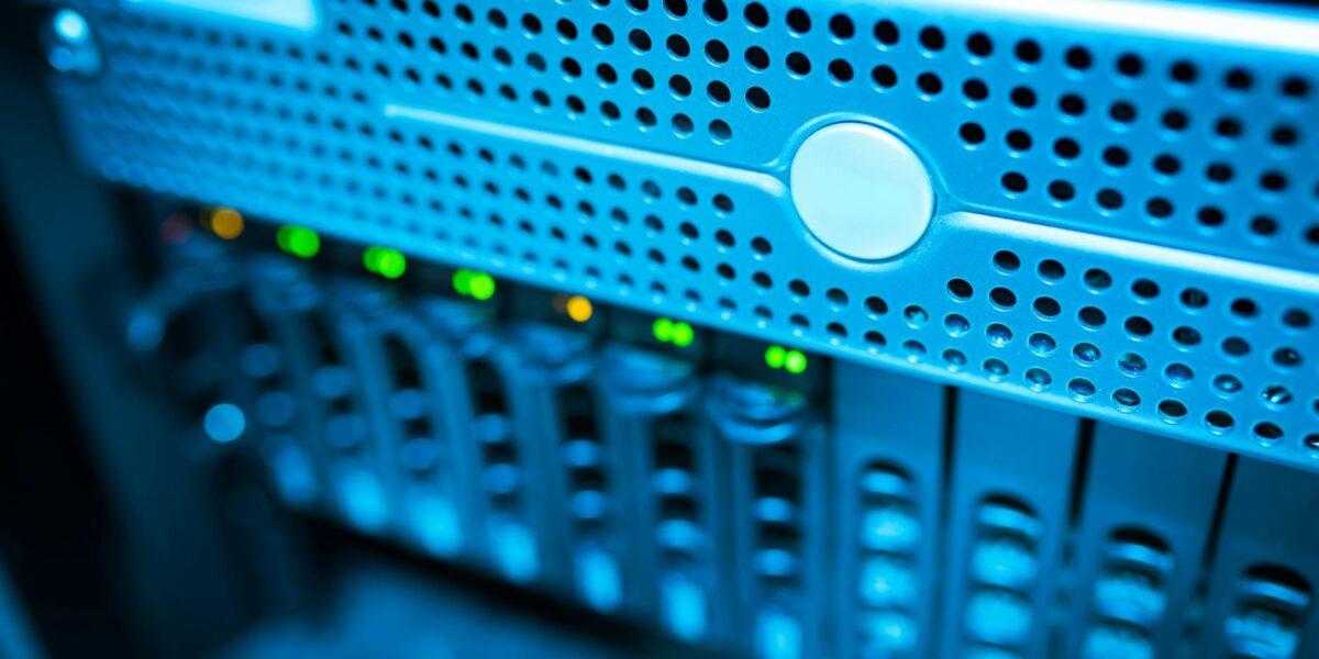 Focused view of a modern data server rack with blinking lights in a blue-lit environment.