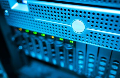 Focused view of a modern data server rack with blinking lights in a blue-lit environment.