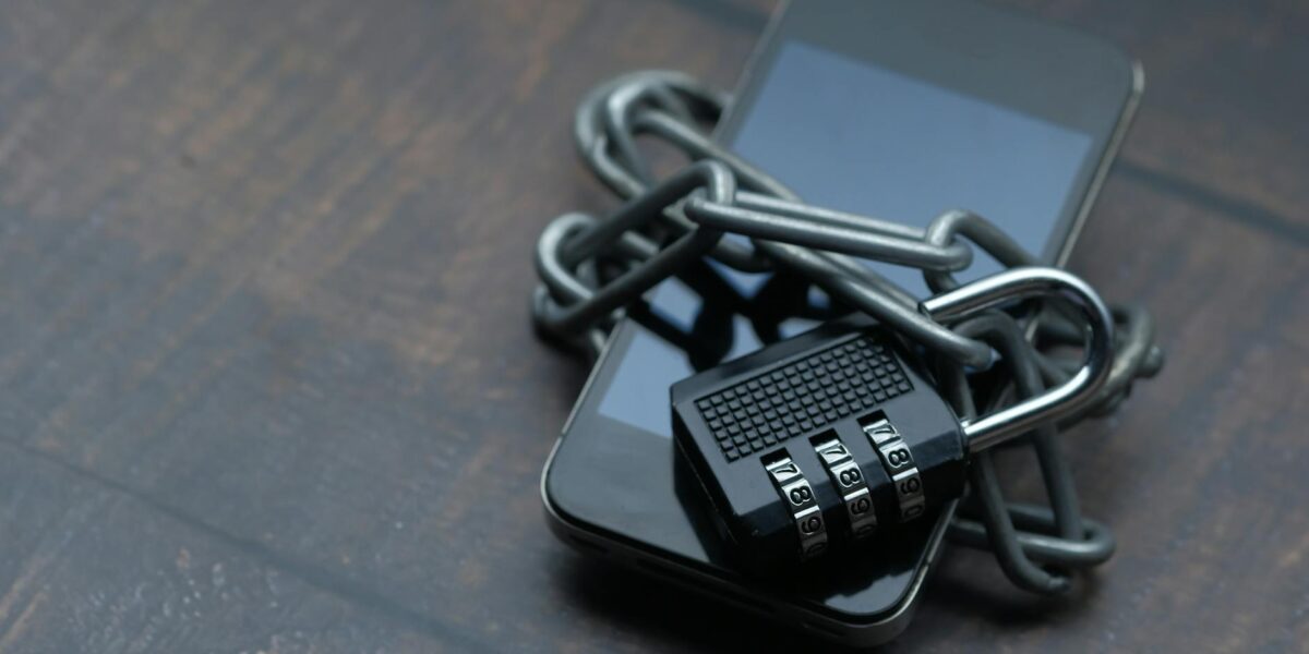 Close-up of a smartphone wrapped in a chain with a padlock, symbolizing strong security.