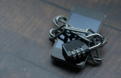 Close-up of a smartphone wrapped in a chain with a padlock, symbolizing strong security.