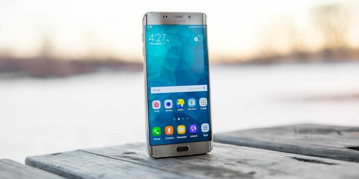 Samsung smartphone placed on a wooden surface outdoors during sunset.