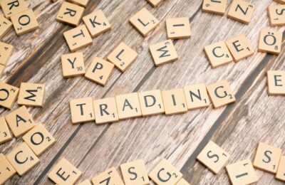 Wooden Scrabble tiles spelling 'TRADING' against a rustic wood background.