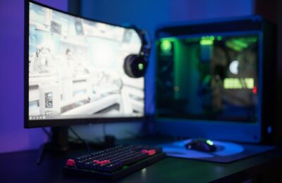 High-tech gaming setup featuring a curved monitor, RGB keyboard, and vibrant lighting.