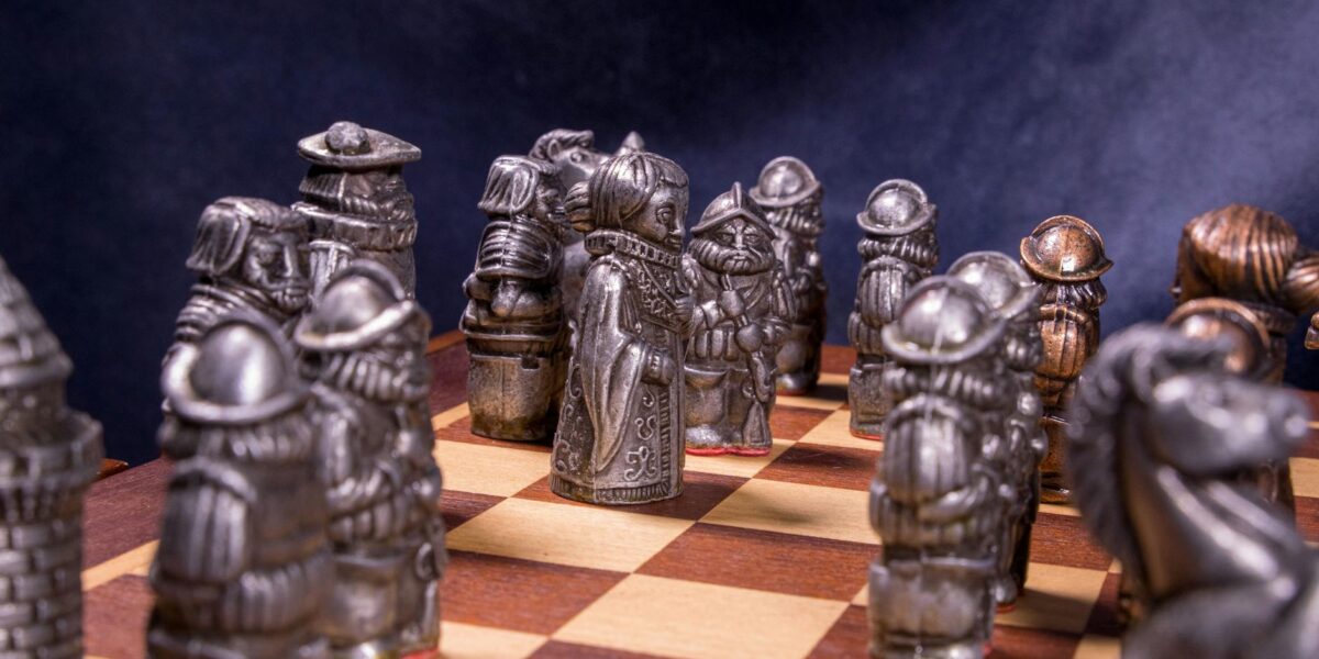 Intricate medieval-themed chess pieces set on a classic wooden board with a dramatic backdrop.